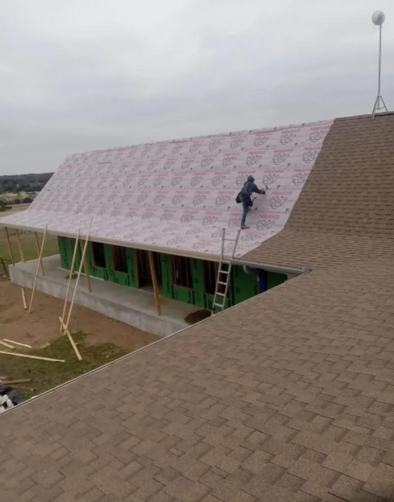 Worker preparing underlayment for a metal roof installation in Duxbury